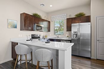 A kitchen with stainless steel appliances and a counter with two stools